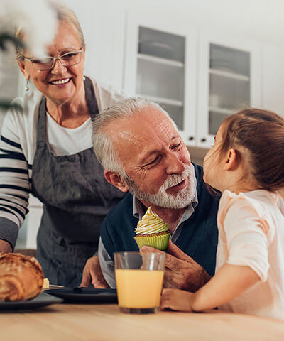 Porque somos asi Pensiones - Pareja senior con su nieta pequeña cocinando magdalenas y sonriendo en la cocina de su casa Porque somos asi Pensiones - Pareja senior con su nieta pequeña cocinando magdalenas y sonriendo en la cocina de su casa