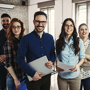Programa Porque somos así - Grupo de personas en fila sonriendo unas al lado de otras en la oficina Programa Porque somos así - Grupo de personas en fila sonriendo unas al lado de otras en la oficina