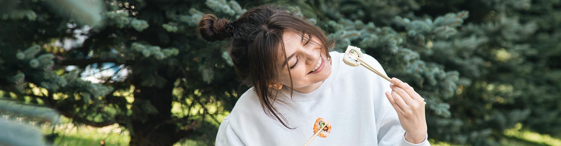 Porque somos así Nuevos clientes - Chica joven prueba por primera vez el sushi sentada en el parque