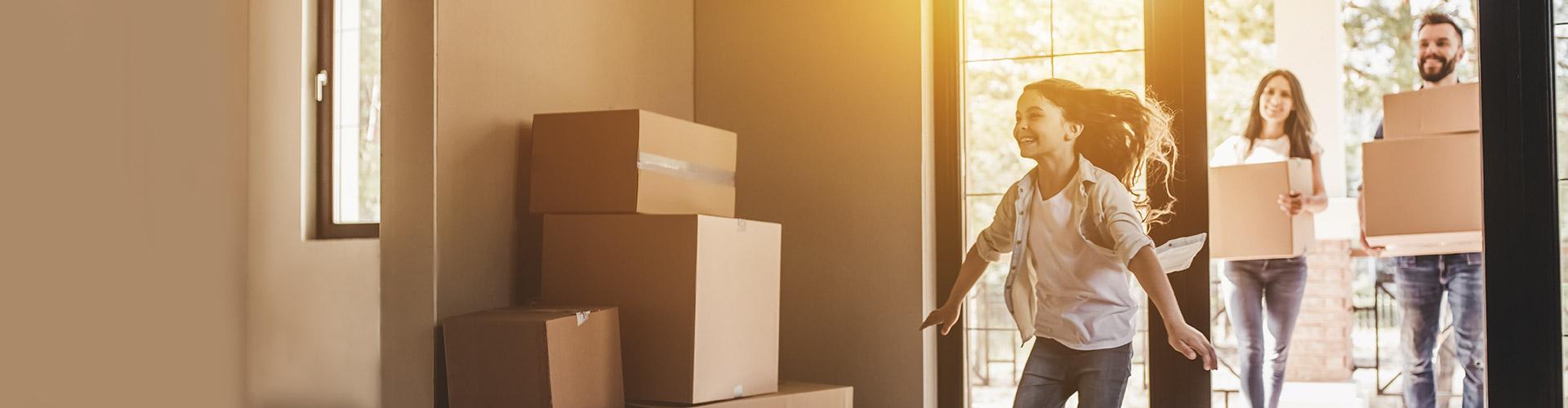 Hipotecas - Pareja con su hija mudándose a su nueva casa felices rodeado de cajas