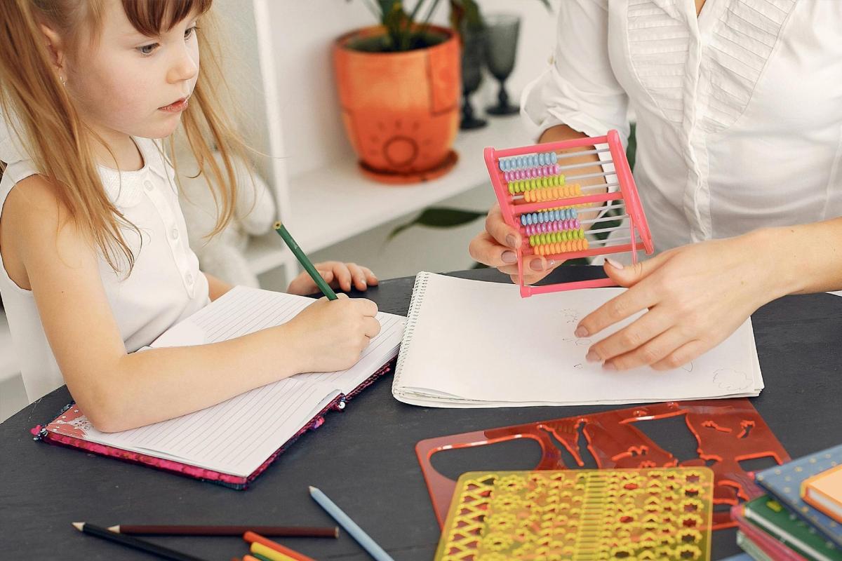 Mujer y niña con lápiz en el colegio