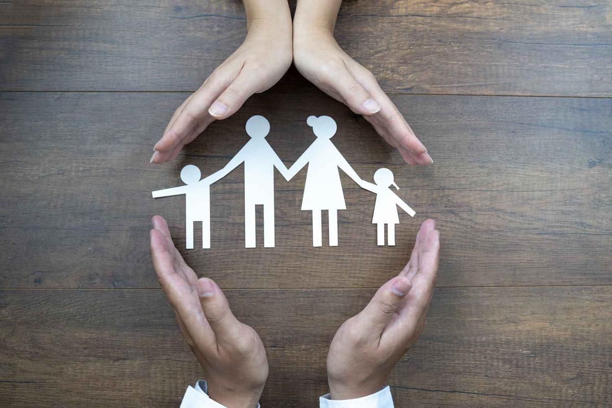 Cerca de manos femeninas y masculinas protegiendo una familia de papel